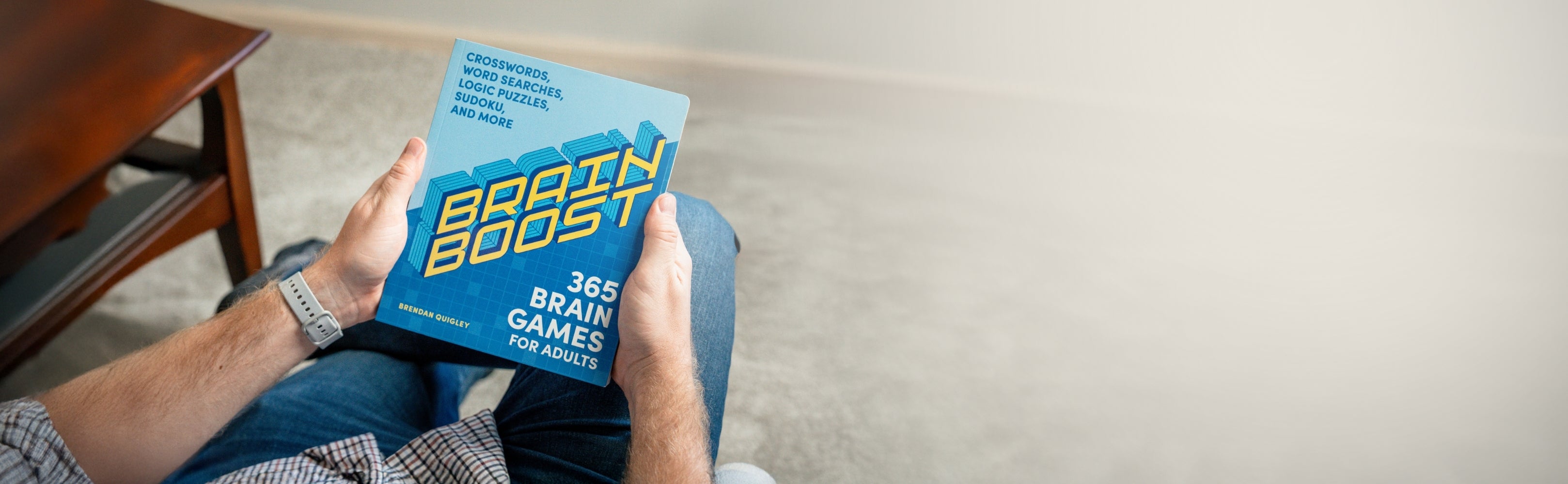 Person holding a book titled 'Brain Boost' on a light-colored floor.